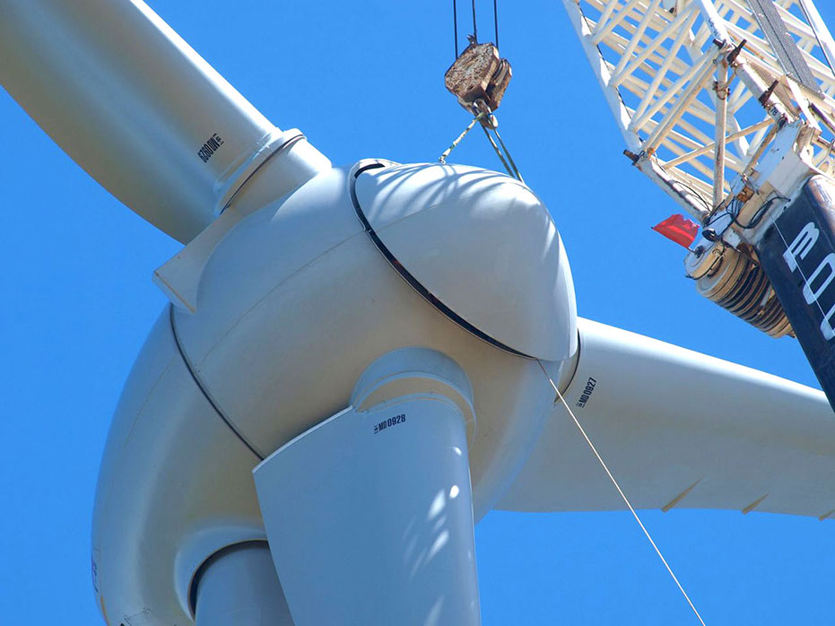 A photo of the spinner being positioned onto the face of the hub and blades assembly to complete the turbine assembly.